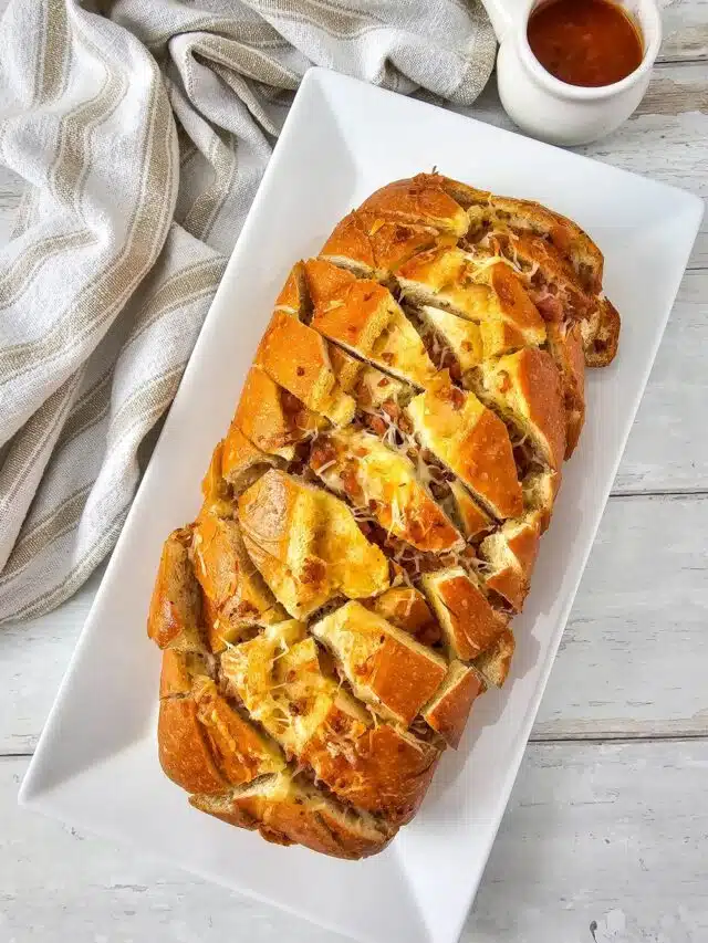 Flat lay shot of the finished Cheesy Pull Apart Bread With Bacon on a rectangular platter.