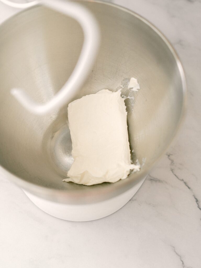 High angle shot of a standup mixing bowl with a block of cream cheese in it.