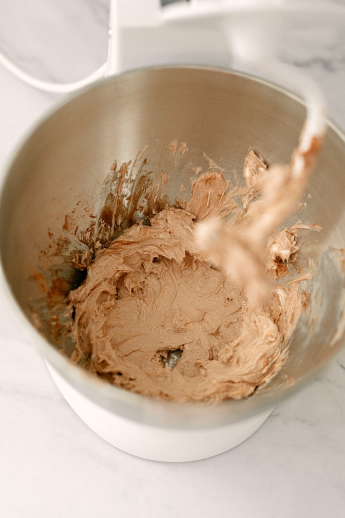High angle shot of mixing bowl with whipped cream cheese with cocoa powder, making it light brown.