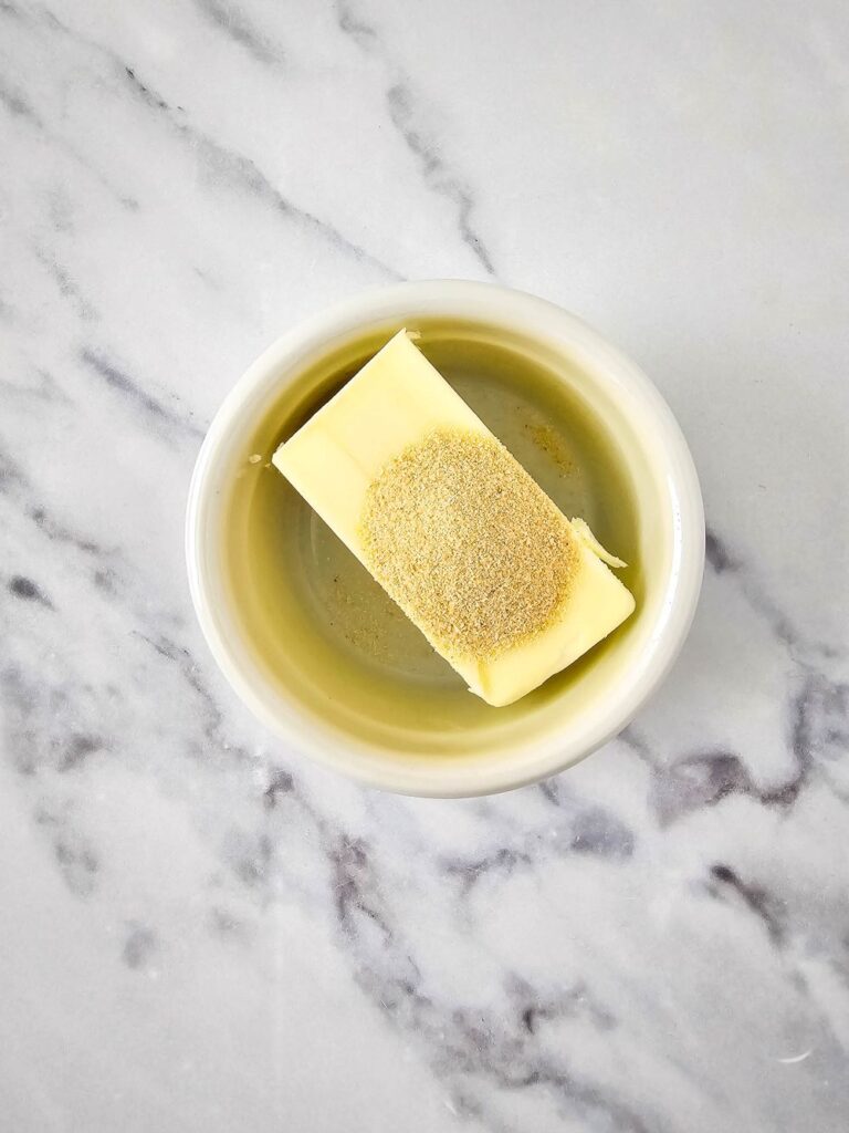 Flat lay shot of a white bowl with butter and seasoning in it.