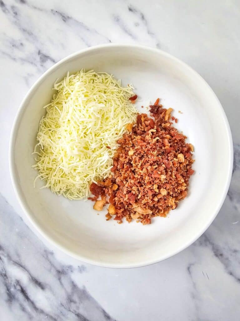 Flat lay shot of a white bowl with cheese and bacon bits.