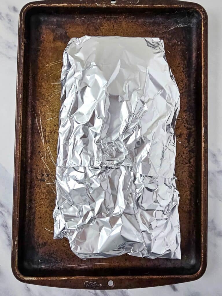Flat lay shot of a loaf of bread wrapped in a sheet of aluminum foil.
