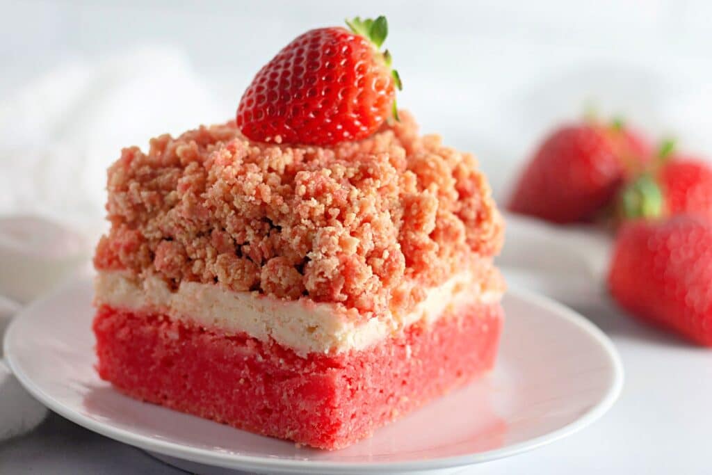 Strawberry Shortcake Crunch Bars with Box Cake Mix 5 A closeup shot of a slice of one of the Easy Strawberry Crunch Cake Bars on a white dessert plate.