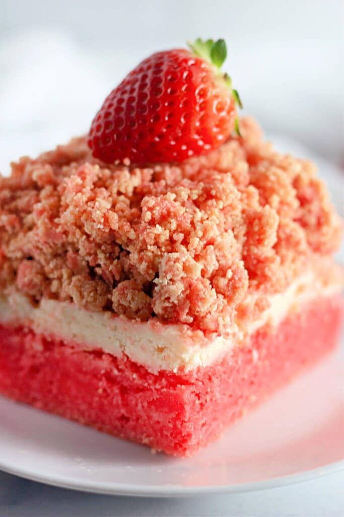Strawberry Shortcake Crunch Bars with Box Cake Mix 15 Closeup shot of a slice of the Easy Strawberry Crunch Cake Bars topped with a single fresh strawberry.