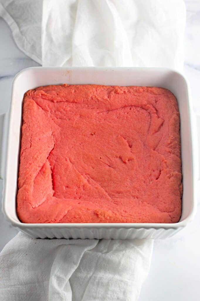 Strawberry Shortcake Crunch Bars with Box Cake Mix 10 A white baking dish with pink cake in it.