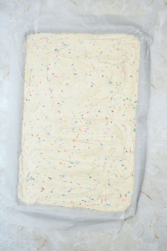 Flat lay shot of the prepared jelly roll tray with the Funfetti cake batter spread out evenly across it. 