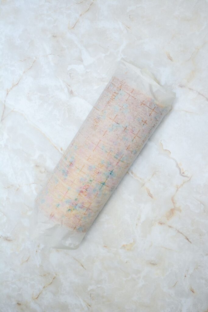 Flat lay shot of the rolled cake within a parchment paper.