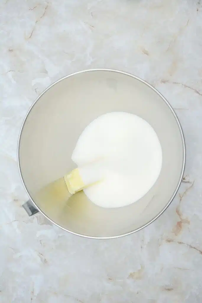 Easy From Scratch Confetti Birthday Cake Roll Recipe with Cream Cheese Frosting 12 Flat lay shot of a mixing bowl with white granulated sugar and a stick of butter in it.