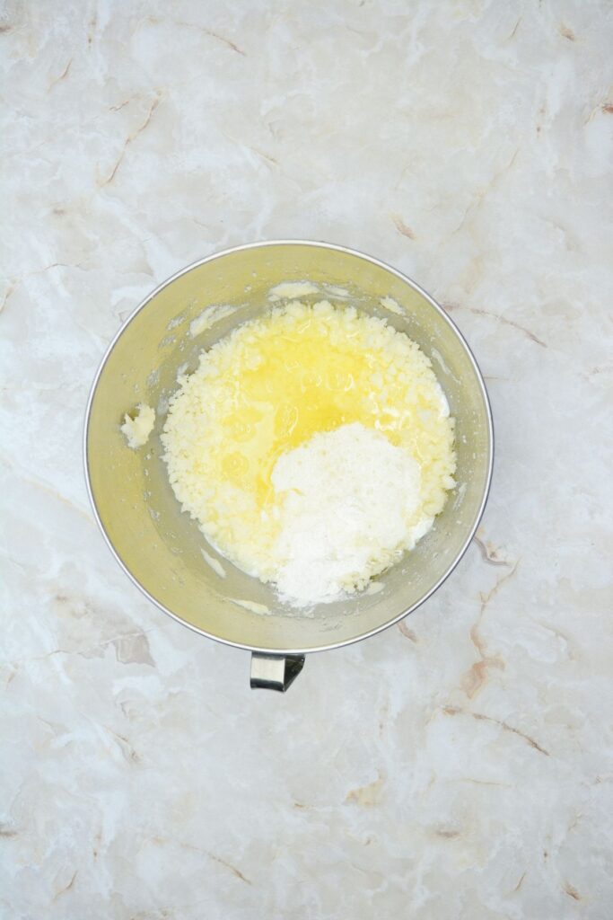 Flat lay shot of a mixing bowl with whipped sugar, butter, eggs and a bit of flour.