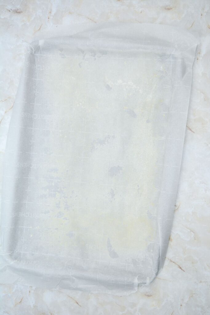 Flat lay shot of a sheet tray with a sheet of parchment paper over it.