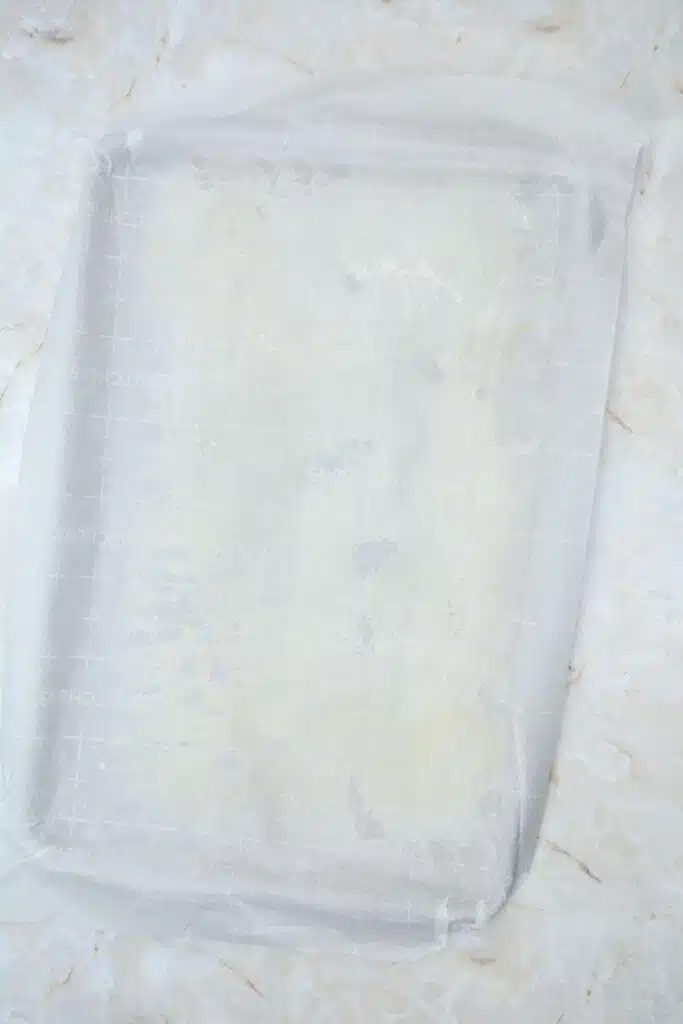 Easy From Scratch Confetti Birthday Cake Roll Recipe with Cream Cheese Frosting 11 Flat lay shot of a sheet tray with a sheet of parchment paper over it.