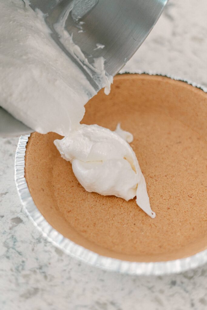 Best No-Bake Strawberry Cream Cheese Pie 9 Cream cheese frosting being transferred into the graham cracker pie crust.