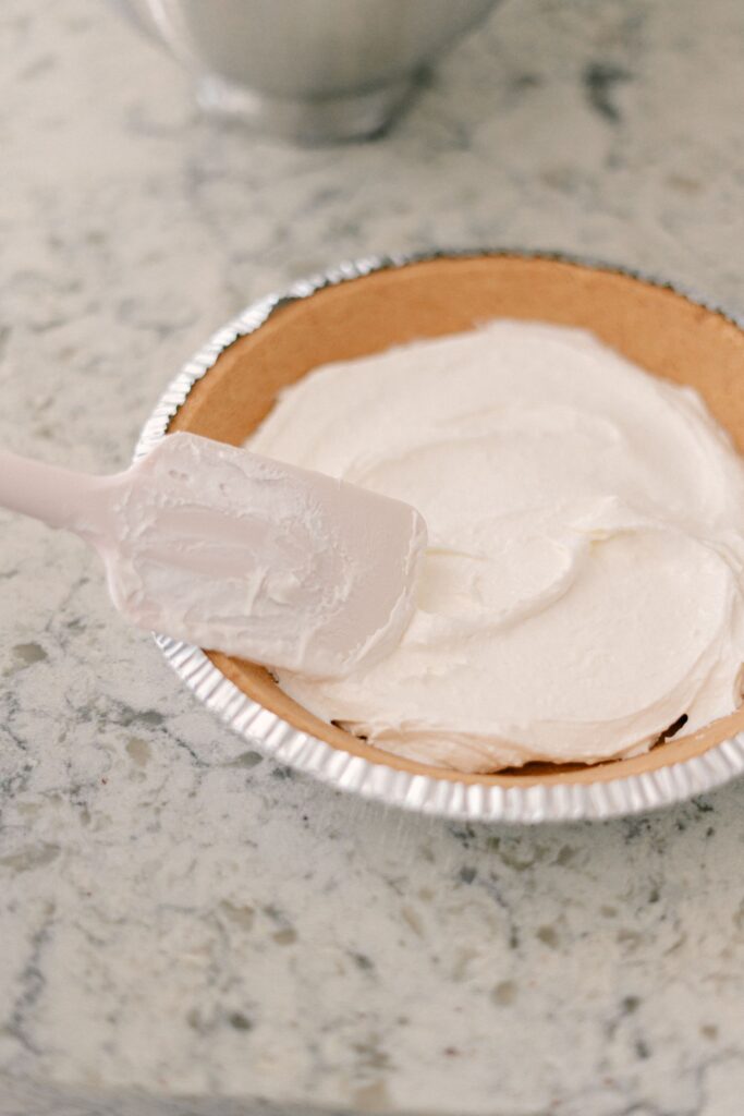 Best No-Bake Strawberry Cream Cheese Pie 10 A white rubber spatula smoothing out the cream cheese mixture on a pie crust.