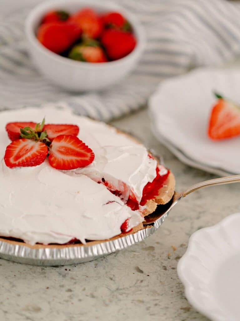 Best No-Bake Strawberry Cream Cheese Pie 4 A slice of The No-Bake Strawberry Cream Cheese Pie being lifted from the whole pie in the aluminum dish.