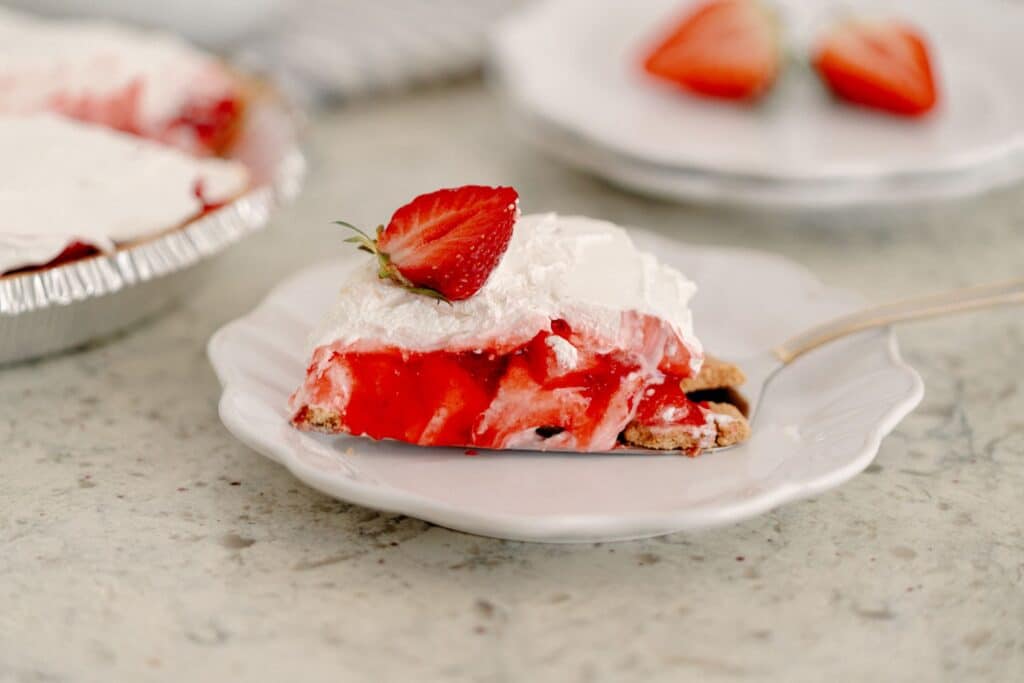 A slice of The Best No-Bake Strawberry Cream Cheese Pie in a white dessert plate.