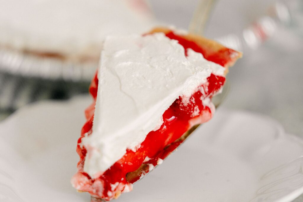 Best No-Bake Strawberry Cream Cheese Pie 18 A slice of The Best No-Bake Strawberry Cream Cheese Pie being placed in a white dessert plate.