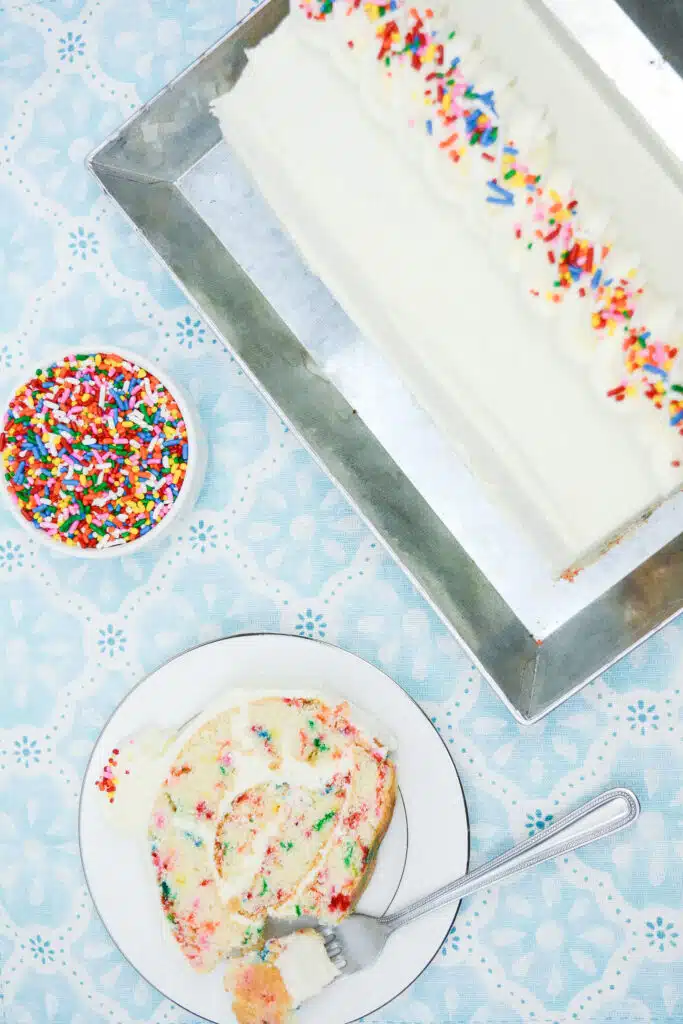 Easy From Scratch Confetti Birthday Cake Roll Recipe with Cream Cheese Frosting 32 Flat lay shot of a slice of Delightful Funfetti Birthday Cake Roll on a white dessert plate.