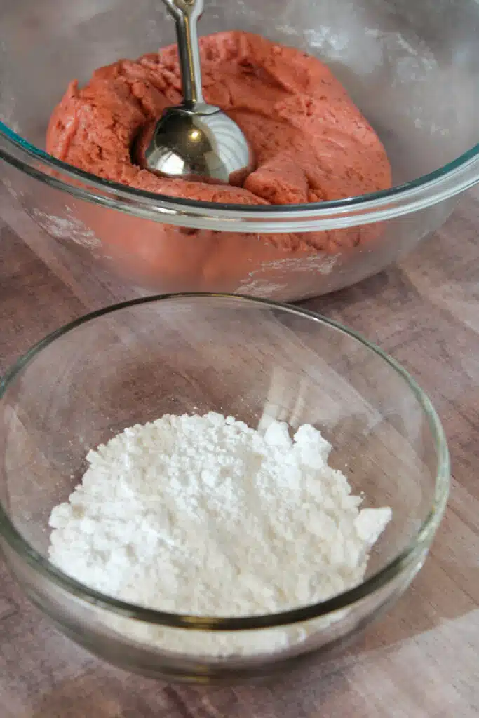 The Easiest Strawberry Cake Mix Crinkle Cookies (4 Ingredients + Vegan!) 9 Powdered sugar in bowl beside of cookie dough for strawberry cookies