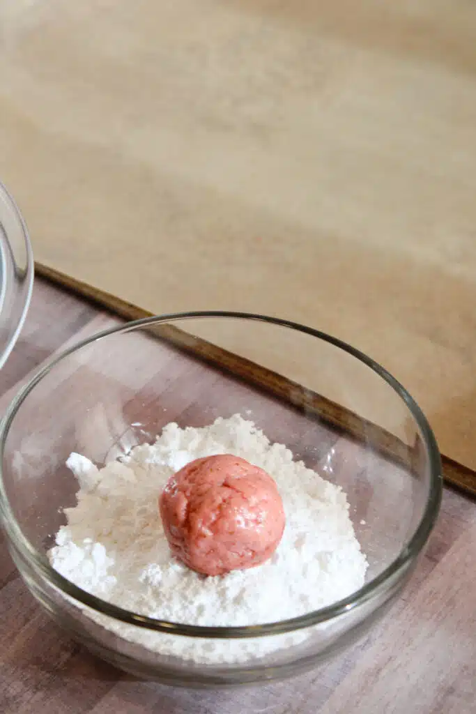 The Easiest Strawberry Cake Mix Crinkle Cookies (4 Ingredients + Vegan!) 11 Strawberry cookie dough being rolled in powdered sugar