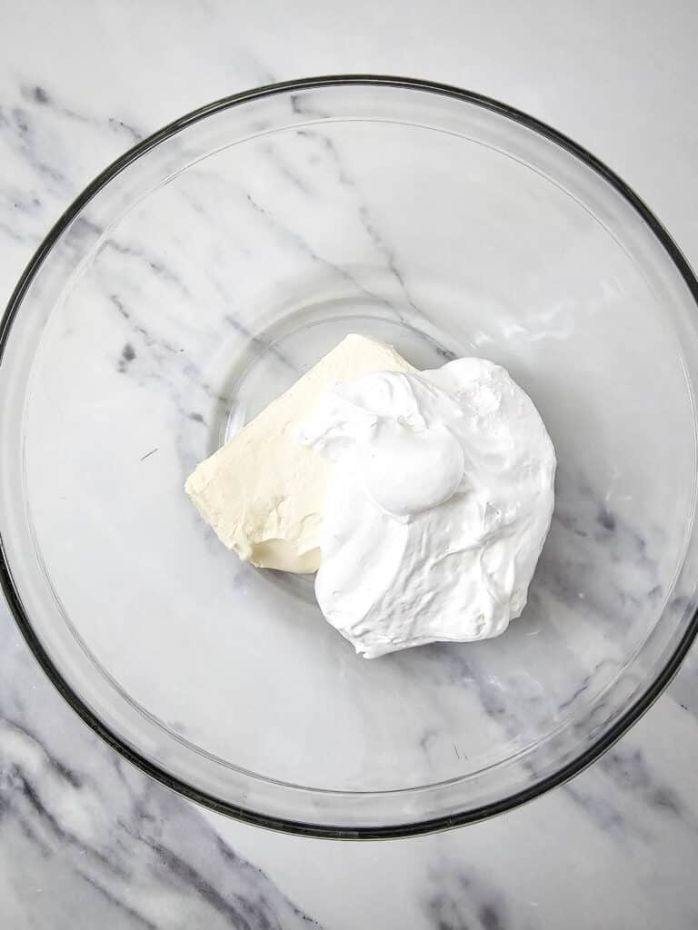Easy 4-Ingredient Cherry Cheesecake Dip 6 Flat lay shot of a glass bowl with a block of softened cream cheese and a huge scoop of marshmallow fluff in it.