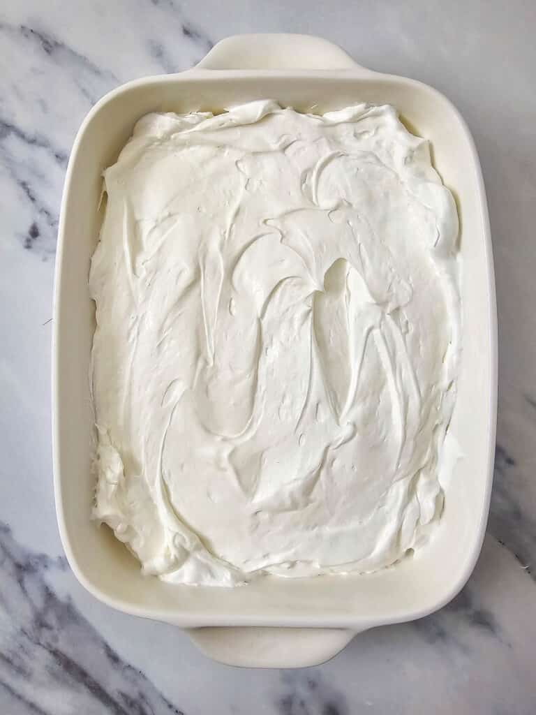 Easy 4-Ingredient Cherry Cheesecake Dip 10 Flat lay shot of a white baking dish with the cheesecake mixture spread evenly across it.