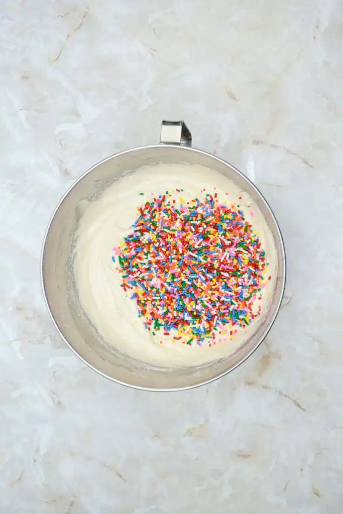 Easy From Scratch Confetti Birthday Cake Roll Recipe with Cream Cheese Frosting 16 Flat lay shot of a mixing bowl with the cake batter and colorful sprinkles added on top of it.