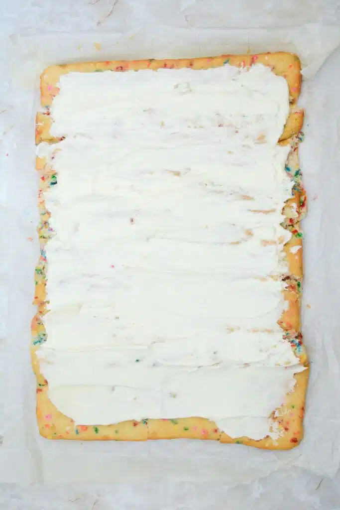Easy From Scratch Confetti Birthday Cake Roll Recipe with Cream Cheese Frosting 25 Flat lay shot of the unrolled Funfetti sheet cake with a layer of cream cheese frosting spread throughout the surface of the cake.
