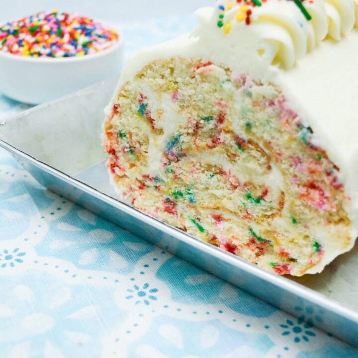 Easy From Scratch Confetti Birthday Cake Roll Recipe with Cream Cheese Frosting 36 A Delightful Funfetti Birthday Cake Roll in a stainless steel platter, with its end sliced to reveal the colorful sprinkle specked interior.