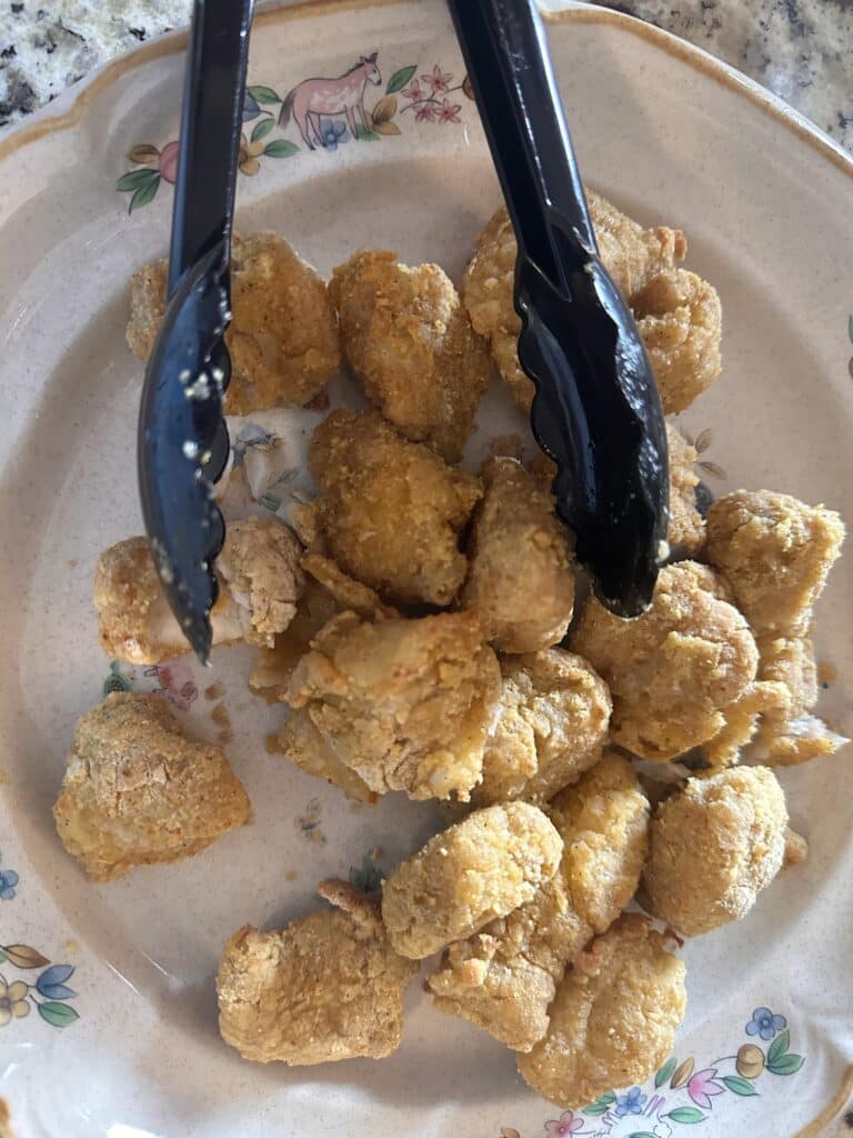 Air Fryer Crispy Catfish Nuggets Flat lay shot of a plate of Air Fryer Crispy Catfish Nuggets with Tongs on plate