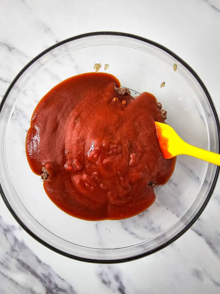 A glass bowl with tomato sauce in it.