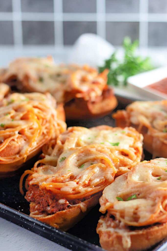 Venison Spaghetti Bread (A Family Favorite!) 4 Focus shot on a batch of Venison Spaghetti Breads in a sheet tray, placed on a kitchen countertop.
