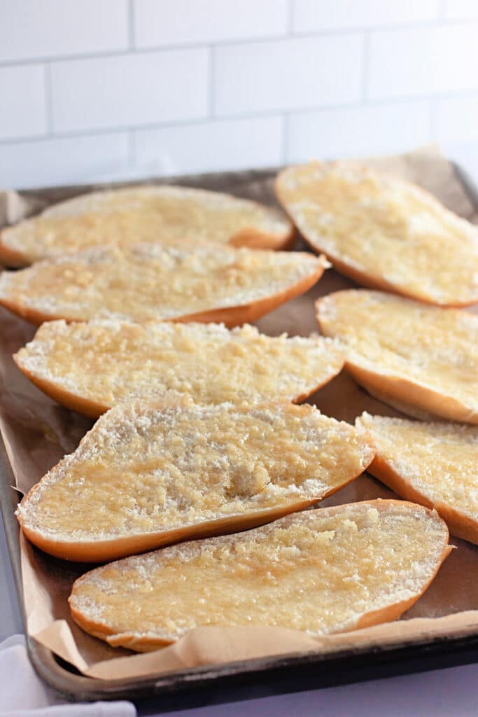 Venison Spaghetti Bread (A Family Favorite!) 11 A sheet pan with halved Hoagie rolls, slathered with melted butter, about to be baked in the oven.