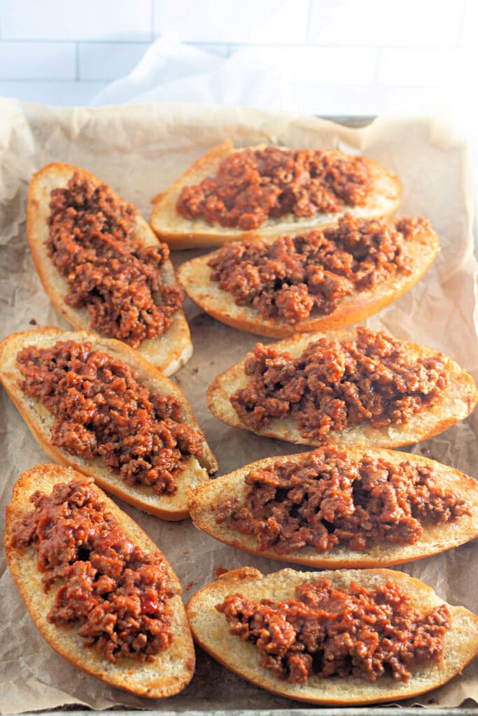 Venison Spaghetti Bread (A Family Favorite!) 13 Eight halved Hoagie rolls topped with meat sauce, on a sheet tray lined parchment paper.