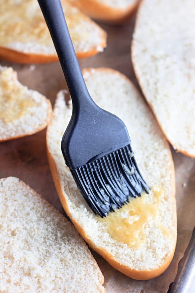Venison Spaghetti Bread (A Family Favorite!) 9 A silicone brush brushing melted butter into a sliced Hoagie roll.