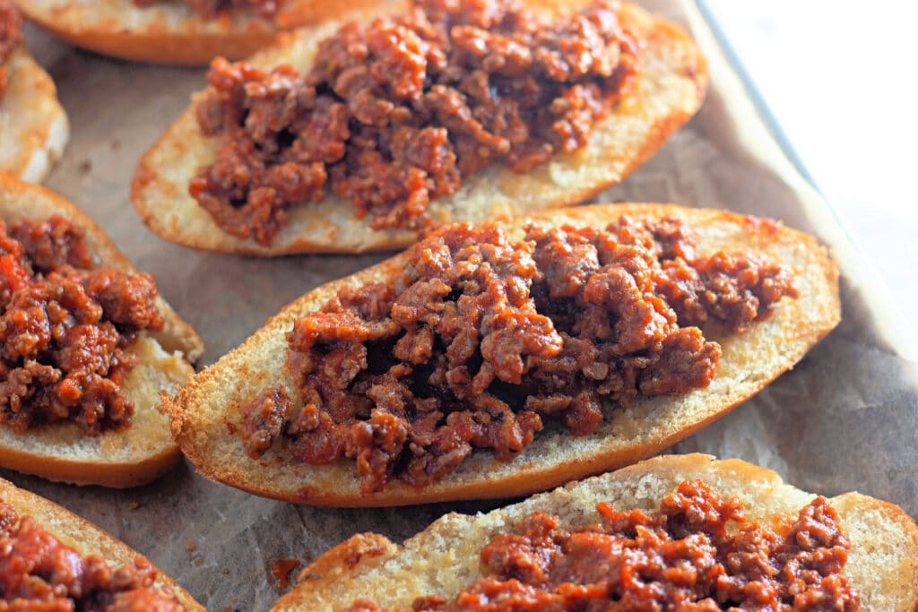 Venison Spaghetti Bread (A Family Favorite!) 21 Closeup shot of a sheet tray with Hoagie halves topped with meat sauce.