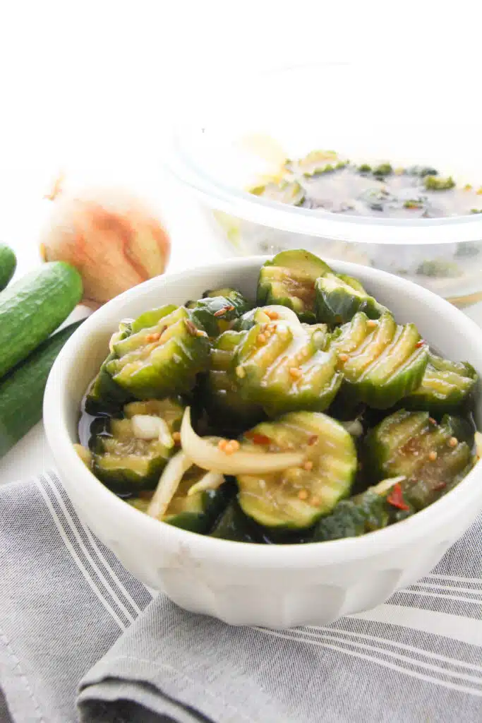 A white bowl with pickles in it.