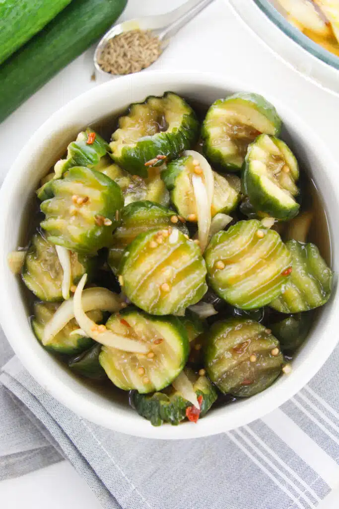A white bowl with pickles in it.