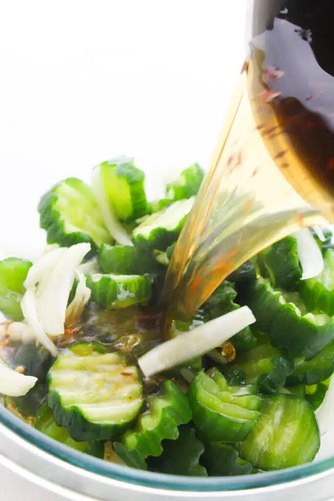 The brine being poured into the sliced cucumbers and onions.