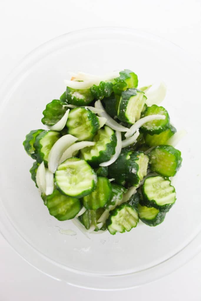 Easy Refrigerator Bread and Butter Pickles 7 Glass bowl with sliced cucumbers and onions.