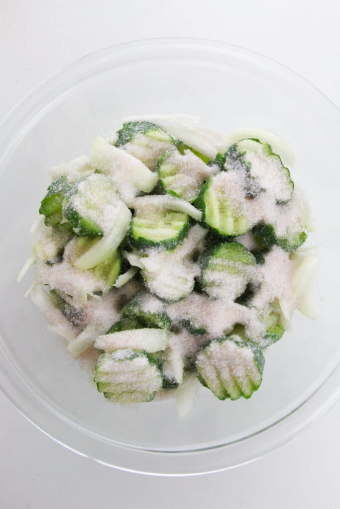 Easy Refrigerator Bread and Butter Pickles 6 A generous amount of salt added to the glass bowl with sliced cucumbers and onions.