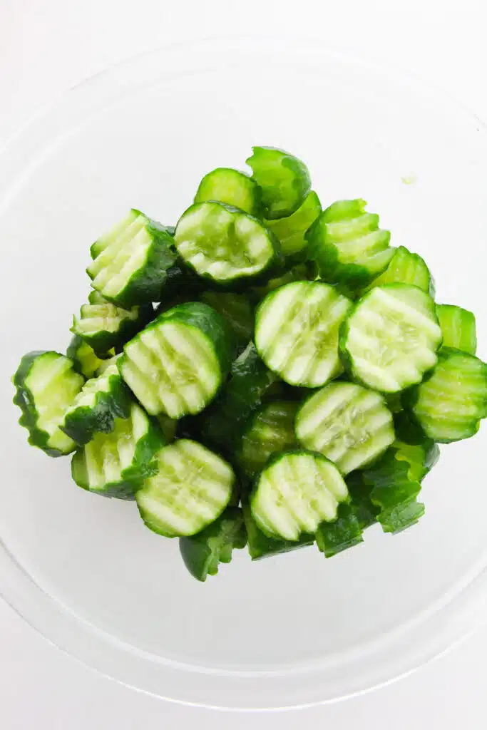 A glass bowl with sliced cucumbers in it.
