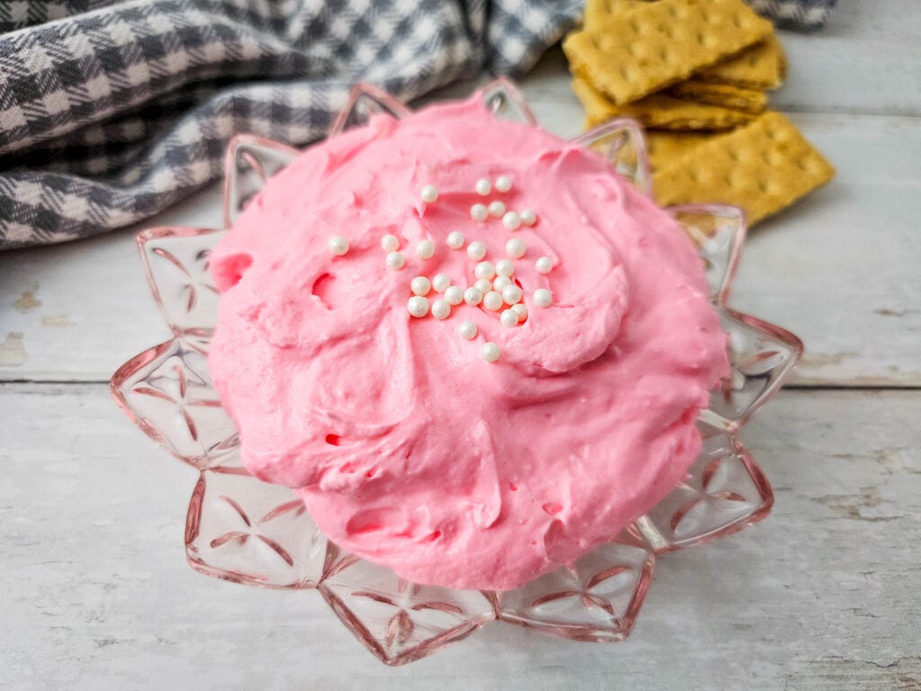 A glass flower like bowl with Pink Marshmallow Fluff Dip in it.