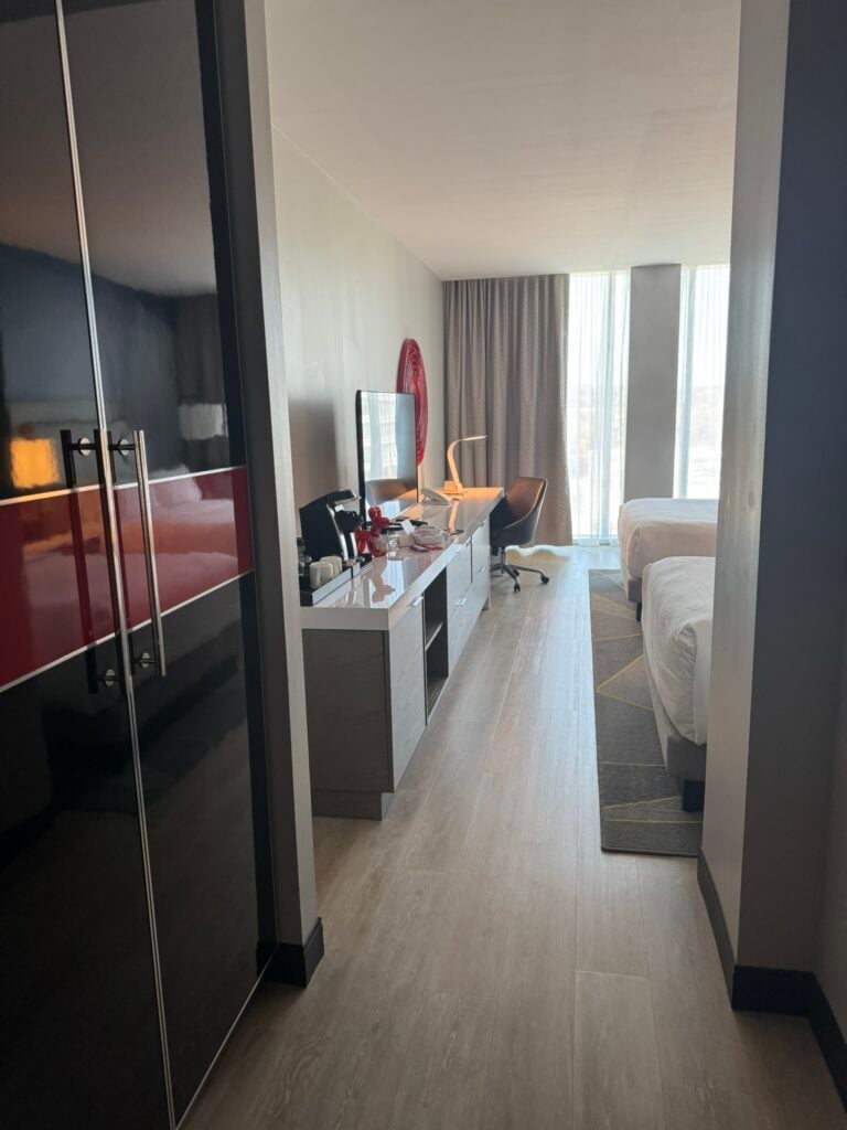 Family-Friendly Hotel in Cincinnati: Our Stay at The Summit Hotel 11 Modern hotel room with two beds, a desk with a computer monitor, an office chair, and floor-to-ceiling windows with curtains letting in natural light.