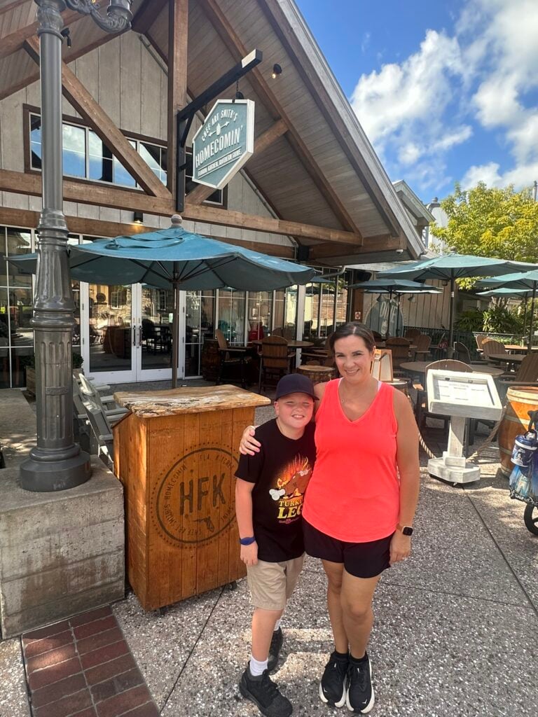 A woman and a boy stand smiling outside Homecomin’—one of the Top 3 Must-Pick Family Friendly Restaurants at Disney Springs—on a sunny day.