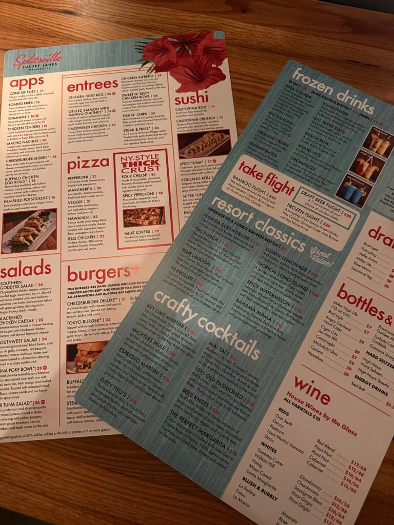 Two restaurant menus on a wooden table showcase appetizers, entrees, sushi, pizza, salads, burgers, and more—perfect for discovering the Top 3 Must-Pick Family Friendly Restaurants at Disney Springs.