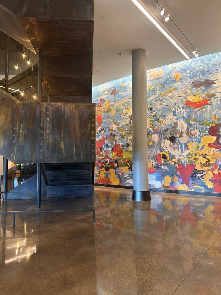 Family-Friendly Hotel in Cincinnati: Our Stay at The Summit Hotel 10 A modern interior with a metal staircase, polished concrete floors, and a large, colorful abstract mural on the wall.